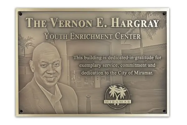 Bronze building dedication plaque with photos of the honoree and building