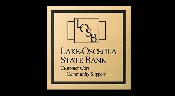 Brass acid-etched metal sign with a financial institution logo and tag line